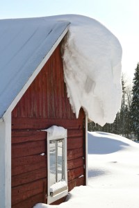 red barn with snow and ice hanging off of roof